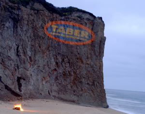 Taber construction logo projected on a cliff-face at dusk. 