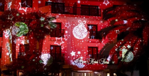 A hotel gets festive with their exterior architectural lighting, projecting giant ornaments and stars against a red wash of color. 