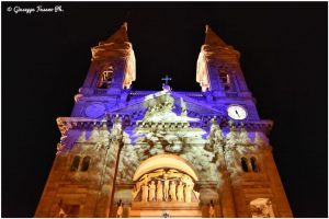 Holiday light displays for public spaces can be temporary art installations like this old church adorned with a wintry forest scene. 