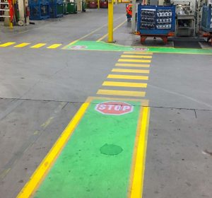 Virtual crosswalk in green and yellow with stop sign projected in a warehouse using a gobo projector. 