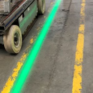 Green virtual walkway line projected next to faded yellow painted walkway. 